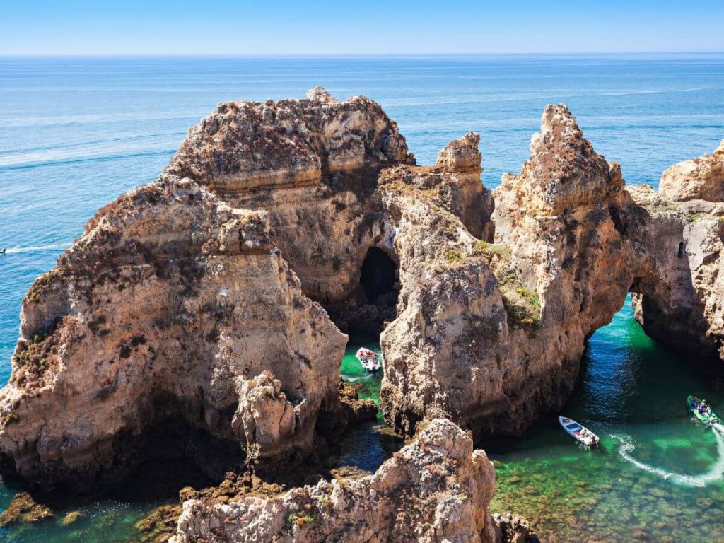 A landscape view of the Ponta da Piedade with three boats amongst the rock formations.