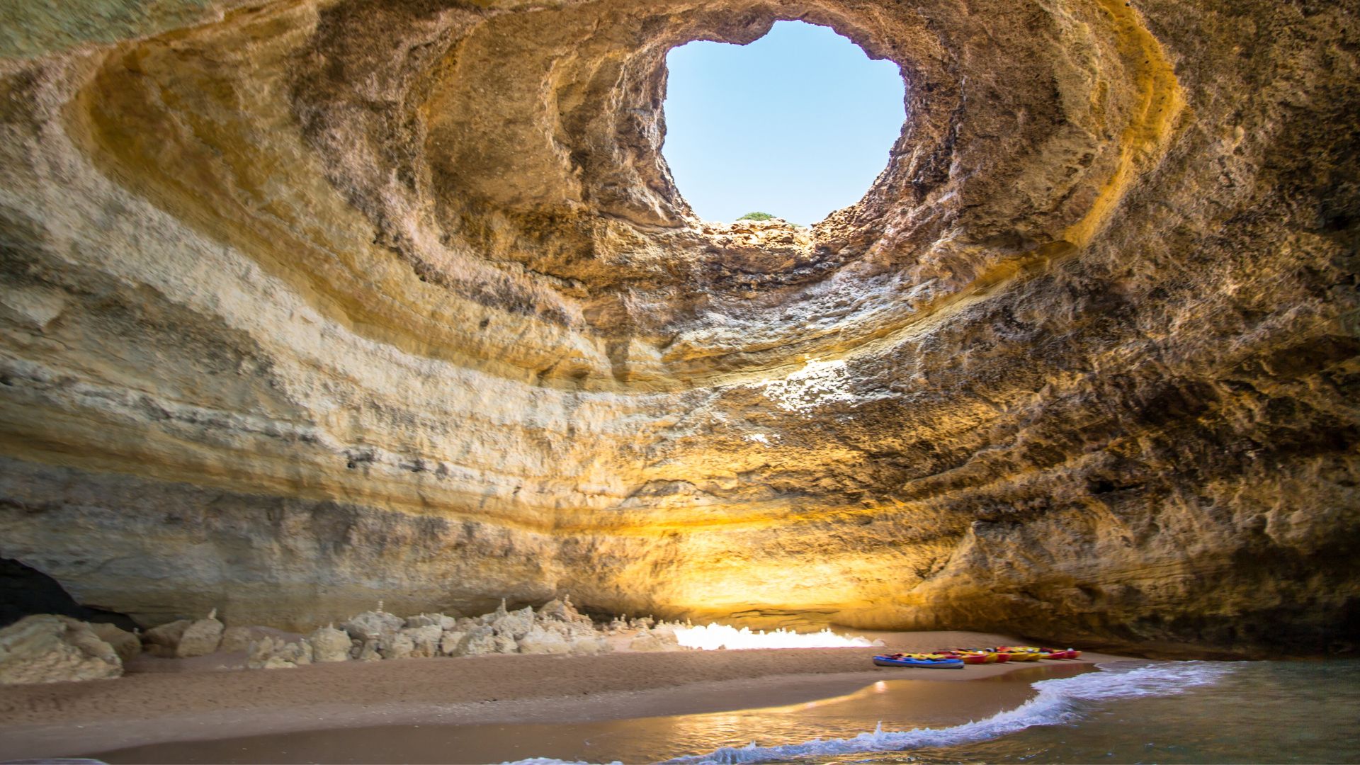 Benagil cave with sunshine coming through the hole in the top of the cave.