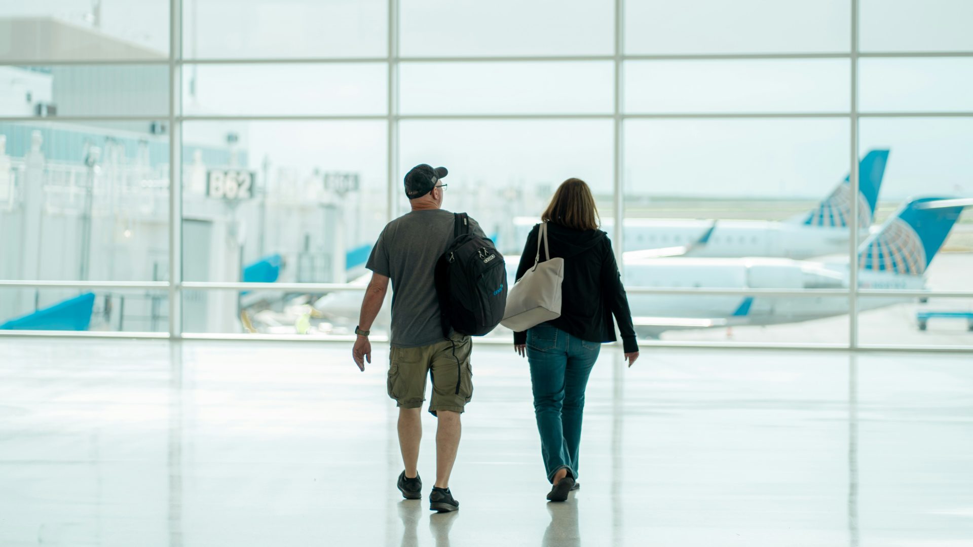 Two people walking through an aiport